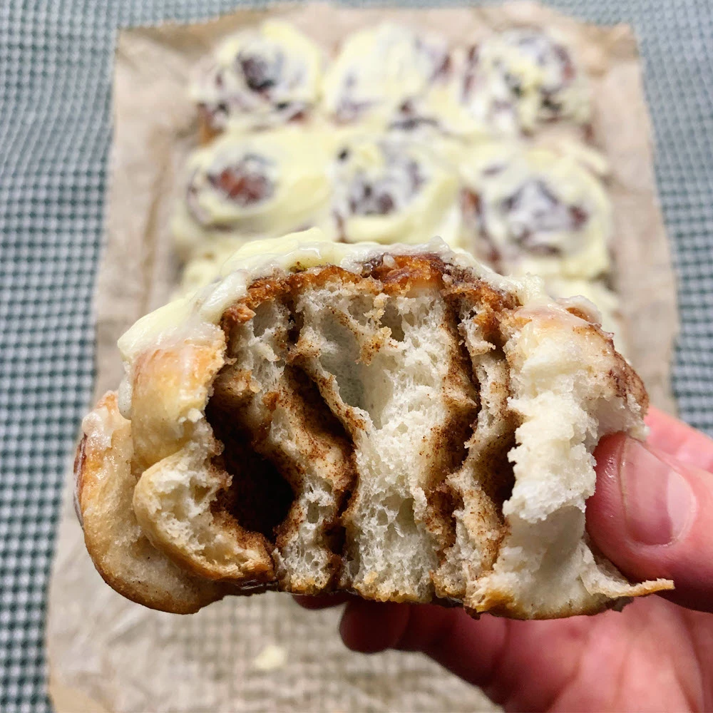 Minkšta ir puri cinamoninė bandelė rankoje